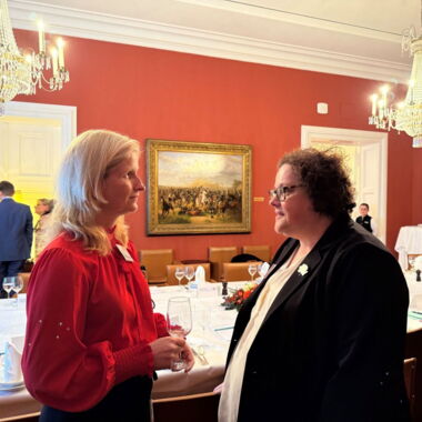 Christiane Möller mit roter Bluse im Gespräch mit Frau Professor Lauber-Pohle, Frau Lauber-Pohle trägt eine weiße Bluse mit einem schwarzem Blazer darüber